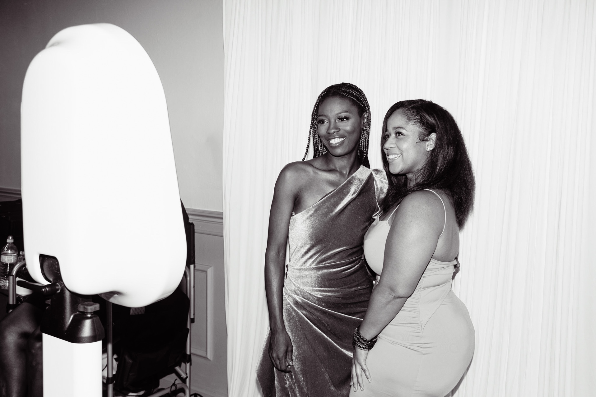 Black and white photo of two guests posing at a MOMNT photo booth kiosk