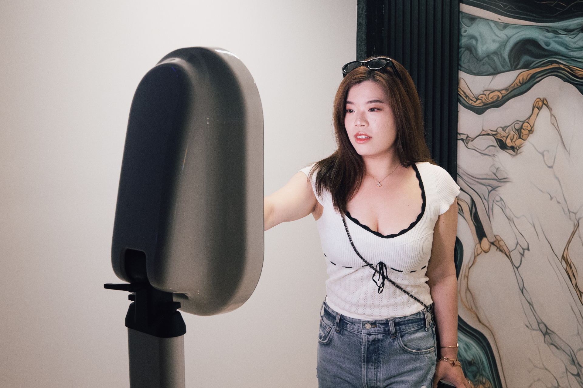 Guest interacting with a sleek oval MOMNT photo booth kiosk at an indoor event